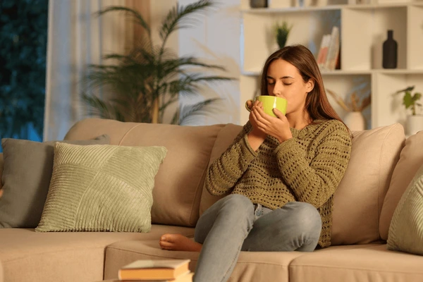 A person enjoying a quiet morning with tea beside an open window